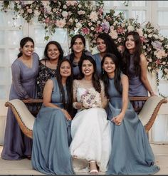 a group of women sitting next to each other in front of a flower covered wall