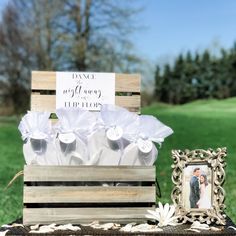 a wooden box filled with white flowers next to a picture frame on top of a table