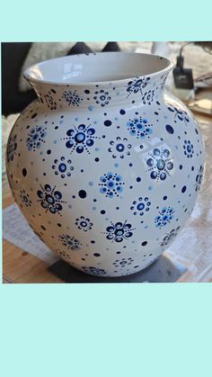 a blue and white vase sitting on top of a wooden table next to a pile of papers