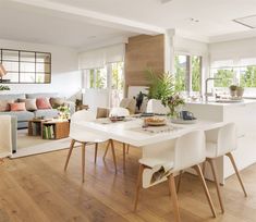 a living room filled with furniture and a white table in front of a kitchen area