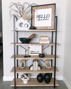 a shelf with books, vases and pictures on it in the corner of a room