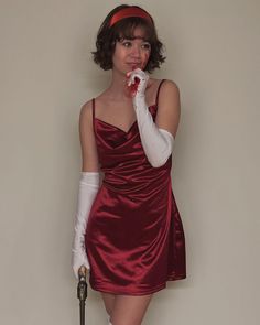 a woman in a red dress and white gloves posing for the camera with an umbrella