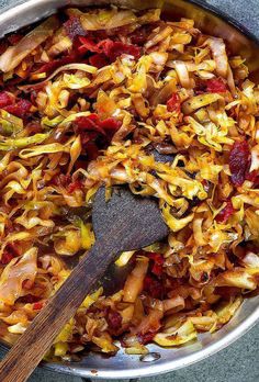 a pan full of food with a wooden spatula in the bottom left hand corner