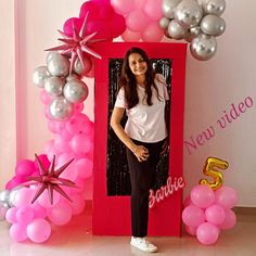 a woman standing in front of a photo frame with balloons and stars on it,