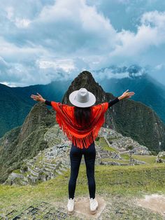 a woman standing on top of a mountain with her arms spread out to the sky