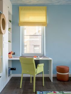 a room with blue walls and yellow blinds on the window sill, green chair in foreground