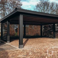 a covered area with brick pavers and trees in the background