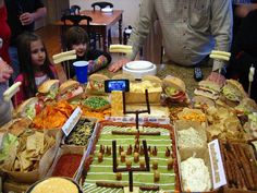 a group of people standing around a table filled with food