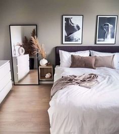 a white bed sitting in a bedroom next to two pictures on the wall and a dresser