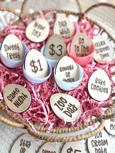 several decorated eggs in a basket with pink shredded paper on the bottom and white labels that say $ 1 each