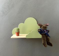 a teddy bear sitting on top of a shelf with a cloud shaped shelf above it