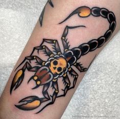 a black and yellow scorpion tattoo on the left arm, with an orange beetle in it's center