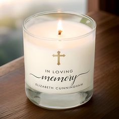 a candle with the words in loving memory written on it sitting on a wooden table