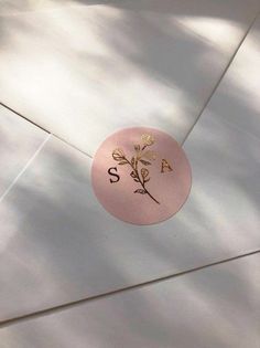 a pink sticker with gold foiling on it that says,'a s '