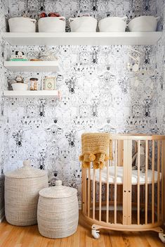 a baby's room with black and white wallpaper, wicker crib and baskets on the floor