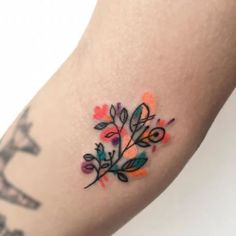 a colorful tattoo on the arm of a woman's left arm, with flowers and leaves