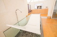 a glass sink in a bathroom with rocks on the ground and wood flooring around it