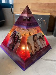 an upside down glass pyramid with pictures on the bottom and lights in the middle, sitting on a countertop