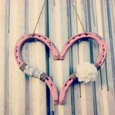 two pink horseshoes shaped like a heart hanging on a wall