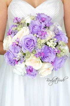 a bride holding a purple and white bouquet