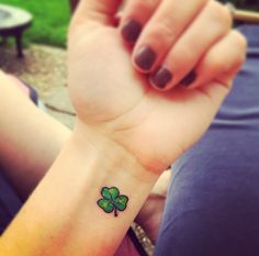 a woman's wrist with a small four leaf clover tattoo on her left arm