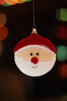 a glass ornament with a santa claus face hanging from it's side