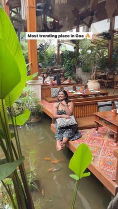 a woman sitting on top of a wooden bench next to a pond filled with fish