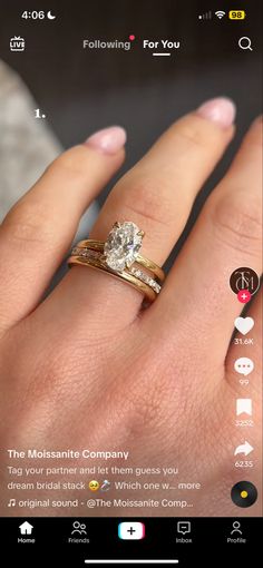 a woman's hand with two gold rings on it and the ring has an oval diamond