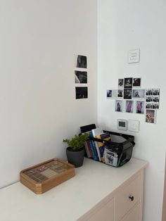 a room with white walls and various pictures on the wall, including a basket full of books