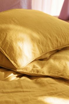 two yellow pillows sitting on top of a bed