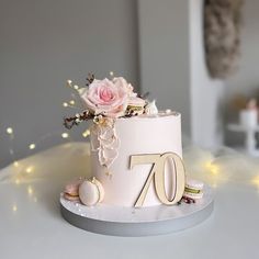 a white cake with pink flowers and the number seventy on it's side sitting on a table