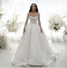 a woman in a wedding dress standing next to flowers