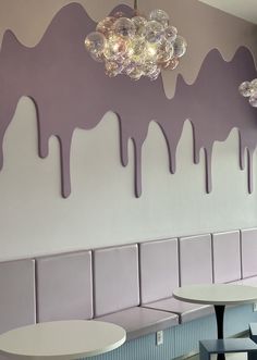 some tables and chairs are in front of a wall with ice cream drizzled on it