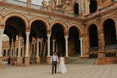 a bride and groom standing in front of an old building with arches on the sides