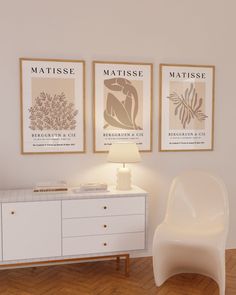 a white chair sitting next to a dresser in a room with two posters on the wall