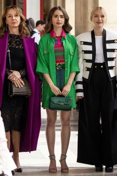 three women standing next to each other in front of a building with columns and pillars