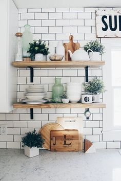 the shelves in this kitchen are filled with dishes and utensils, while plants sit on top of them