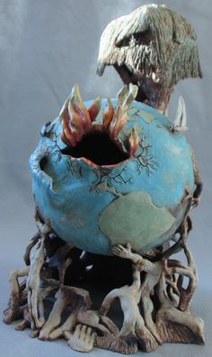 a blue vase with an animal head sticking out of it's mouth and roots