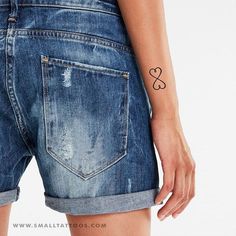 a woman with a heart tattoo on her left arm, wearing blue jeans and shorts