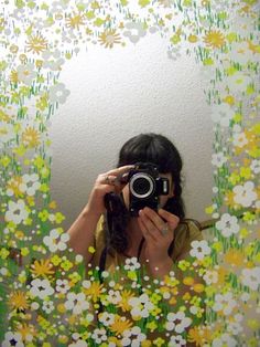 a woman taking a selfie in front of a mirror with flowers all over it