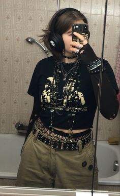 A mid-sized person/girl wearing a    black cropped graphic shirt, wide brown cargo shorts, black skull headphones, black cobweb tights, platform dr. Martens and multiple dark green and gray crystal rings and bracelets. 		The person is also wearing multiple silver necklaces. Goth Mid Size, Masc Goth Outfits Plus Size, Masc Maximalism, Alt Punk Fashion, Alt Enby Fashion, Punk Outfit Inspiration, Punk Outfits Diy, Plus Size Alt Fashion Masc, Masc Button Up Outfits