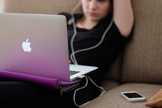 a woman sitting on a couch with her laptop and headphones in her hand, listening to music