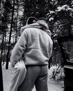 a man standing in the snow with his back to the camera, wearing a jacket and pants