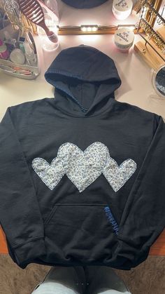 a black hoodie with hearts on it sitting on top of a table next to a pair of shoes