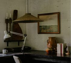 a table with a lamp and some books on it next to a framed painting hanging from the wall