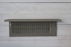 a gray mailbox mounted to the side of a white wooden wall with wood planks