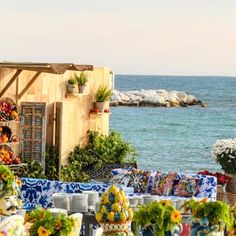 an outdoor dining area overlooking the ocean with tables and chairs covered in colorful cloths