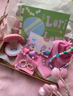 pink items are sitting in a box on a table next to flowers and a card