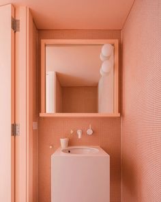 a small bathroom with pink walls and flooring is pictured in this image, there is a mirror on the wall above the sink