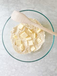 a glass bowl filled with flour and butter next to a wooden spoon